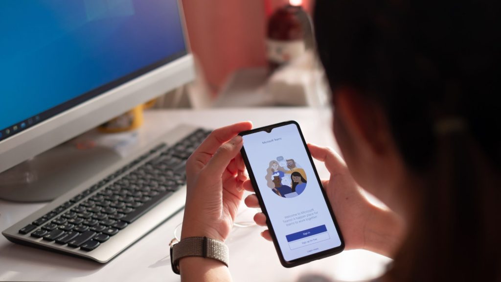 Woman holding a phone with Microsoft Teams starting